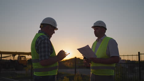 Retrato-De-Manos-De-Dos-Constructores.-Constructor-Estrechando-La-Mano-Al-Constructor-Sobre-El-Fondo-De-La-Casa-Construida.-Primer-Plano-De-Un-Apretón-De-Manos-De-Dos-Hombres-Con-Chalecos-De-Señales-Verdes-Contra-El-Fondo-Del-Sol