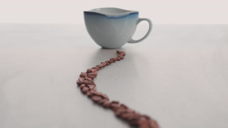 granos de café dispuestos artísticamente y una taza de diseño único y tradicional - toma de primer plano