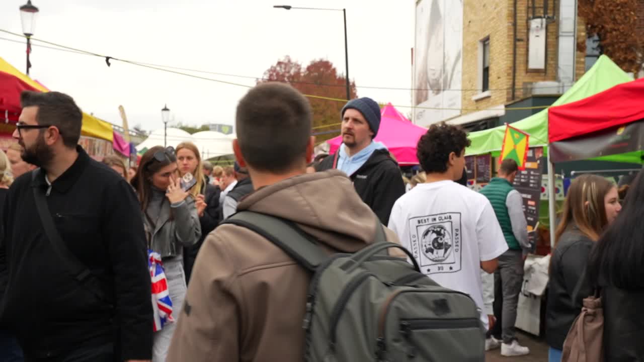 Tourist walking in the crowded street food market of Portobello Road, London