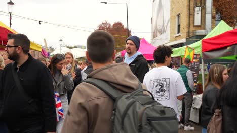 tourist walking in the crowded street food market of portobello road, london