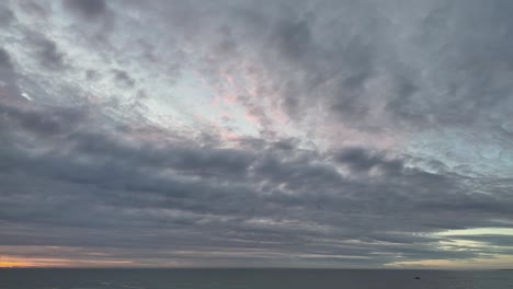 time lapse of textured clouds moving over the ocean during the transition to sunset.