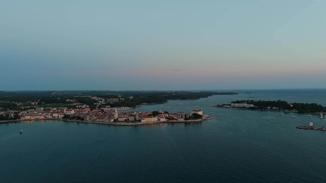 Parenzo Croazia al tramonto, vista aerea con drone della splendida città vecchia, hotel costieri, spiagge soleggiate, lungomare, ruota panoramica e giostre durante una calda serata estiva sulla costa adriatica