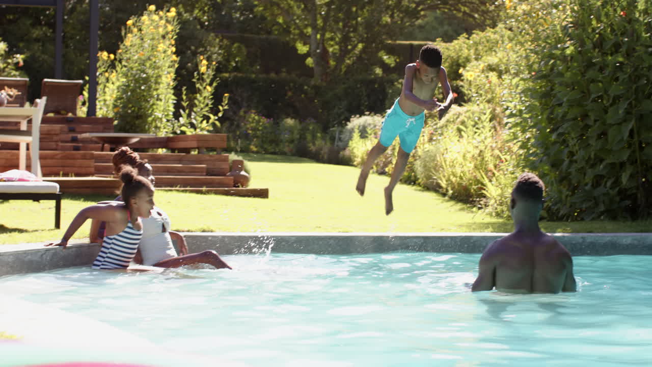 Sort bror og søster leger i swimmingpool, nyder sommerdagen med familien.