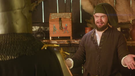 happy merchant deals with adventurer in tavern. plump bearded man shrugs hands after good trade with wayfarer in store. dwarf seller and night guest