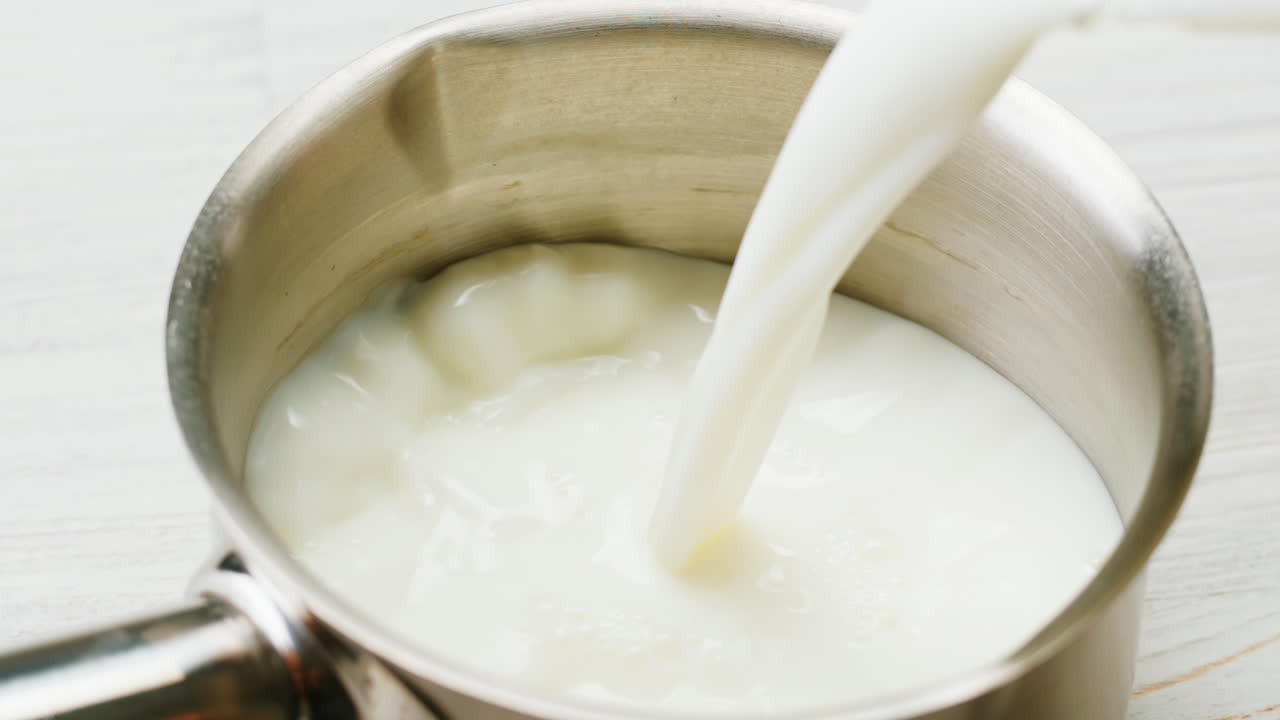 наливать молоко в кастрюлю