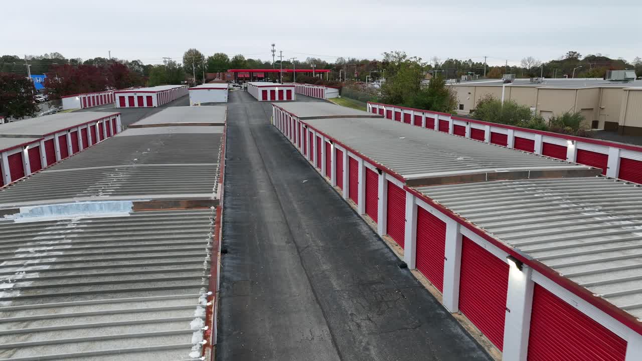 Aerial flyover red garages of warehouse temporary buildings in America suburb. Cloudy day in fall season. Row of rental gerate units of American town