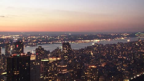 a vibrant aerial shot of new york's skyline at sunset with city lights shining brightly over the hudson river
