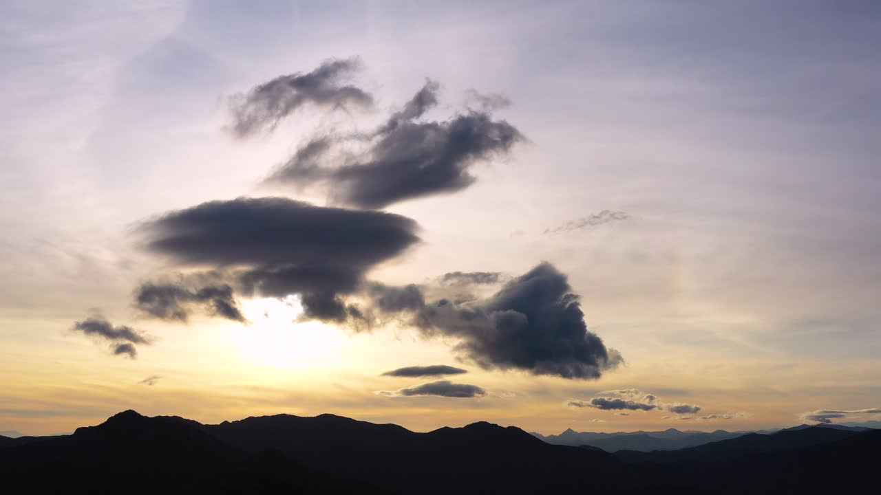 프랑스 남쪽의 구름이 가득한 노란 하늘에서 산에서 해가 지는 모습