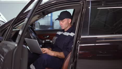 Mechanic-working-on-laptop-in-auto-repair-service-inside-the-car,-close-up