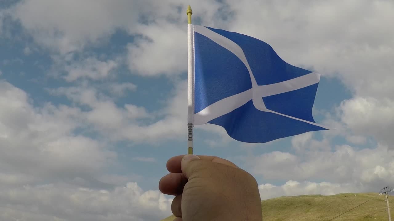Et skotsk flag holdt i hånden vajer på himlen
