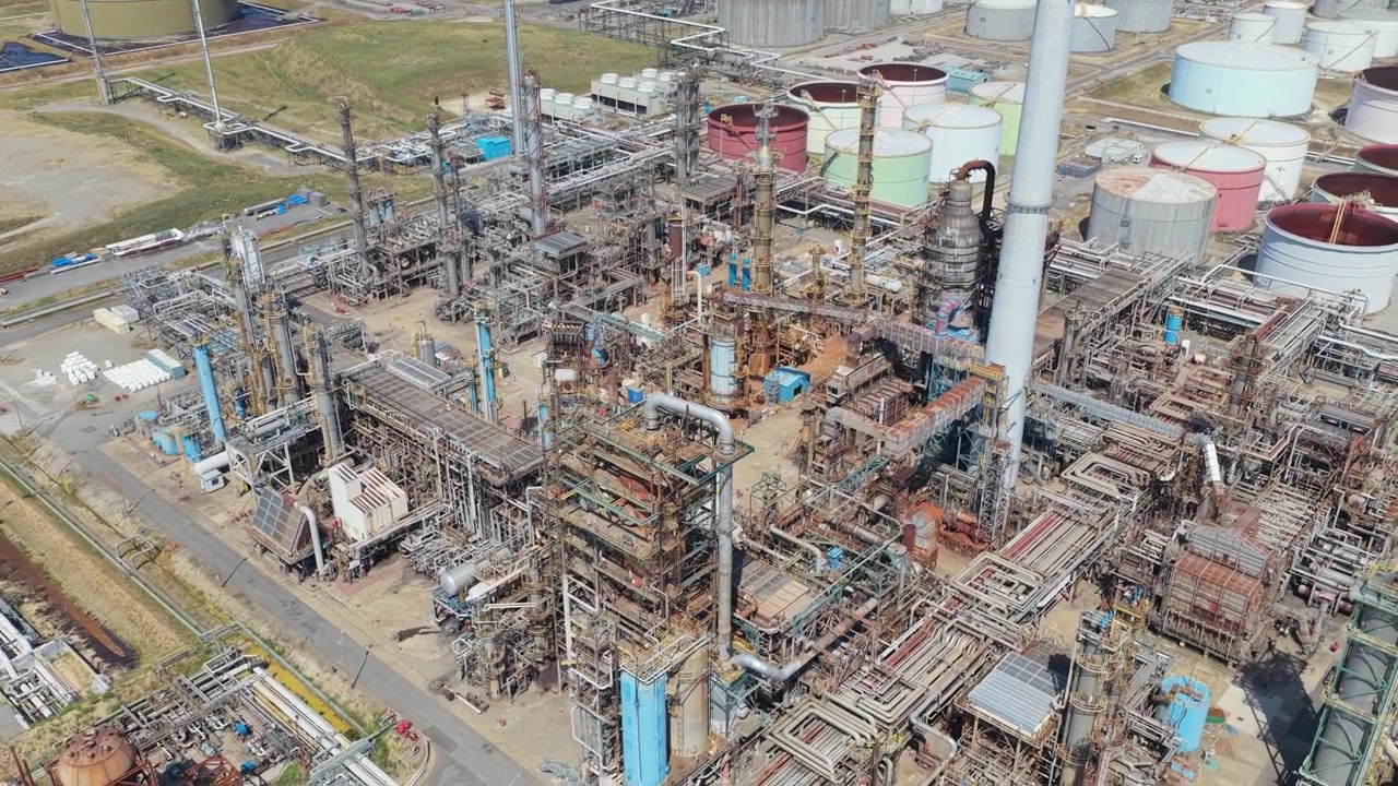 Complesso industriale di raffineria di petrolio che mostra grandi serbatoi di stoccaggio e tubazioni metalliche durante una giornata di sole splendente, nelle ore diurne, mentre lavora prodotti chimici e prodotti petroliferi per la produzione globale di energia