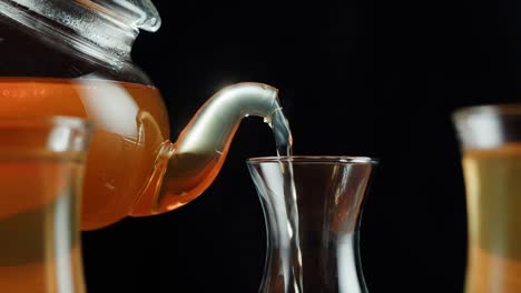 hot tea pouring from teapot into glass cup