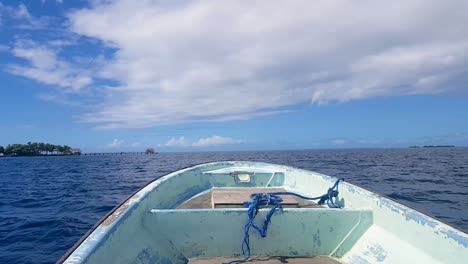 sitting in a small motorboat overlooking the front bow of boat approaching small, remote tropical island of nahlap in pohnpei, micronesia, over calm blue ocean on sunny day