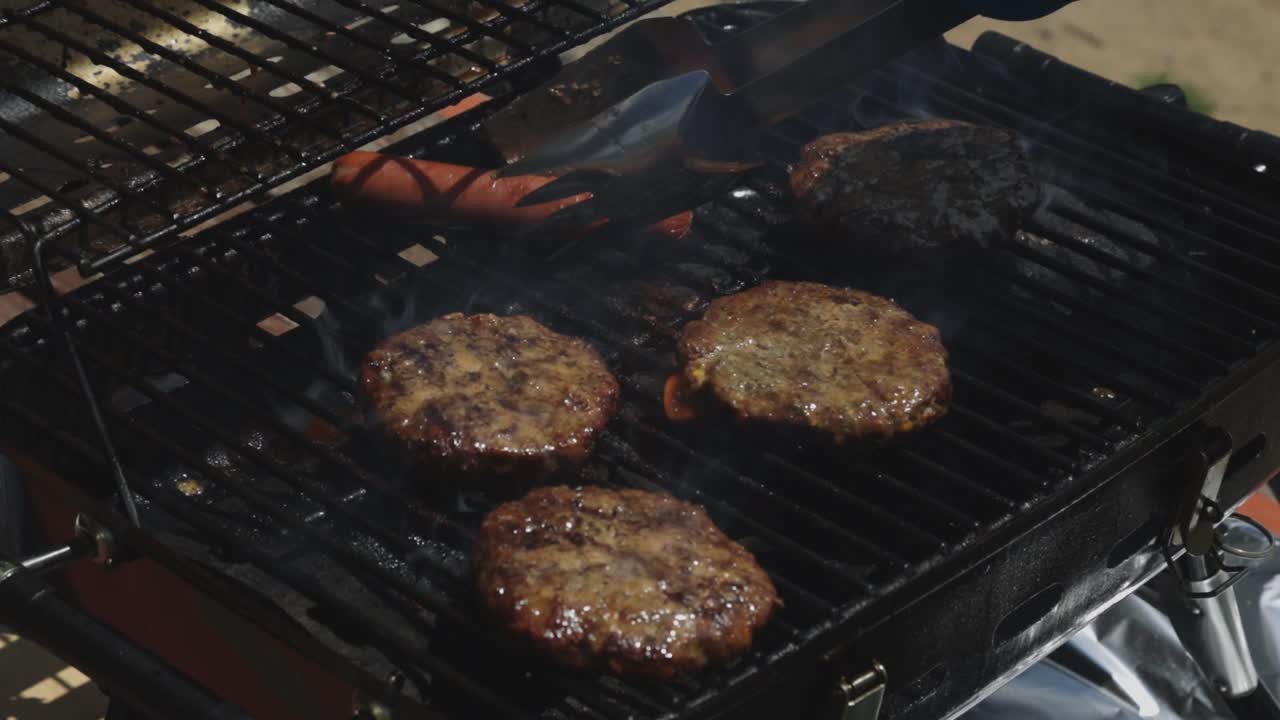 Salsicce e hamburger grigliati sulla brace sulla griglia del barbecue