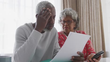 Ein-älteres-Afroamerikanisches-Paar,-Das-Zu-Hause-In-Sozialer-Distanz-An-Papieren-Arbeitet