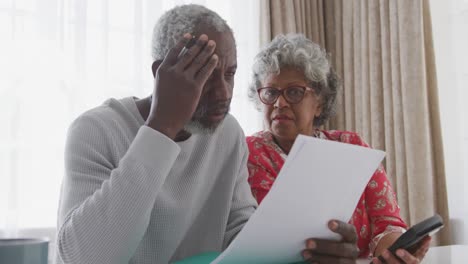 una pareja afroamericana mayor en casa trabajando en papeles en distancias sociales