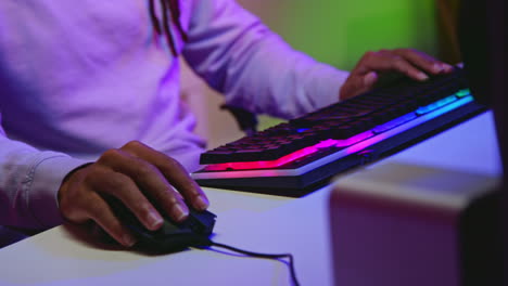 man playing on computer with rgb keyboard and mouse