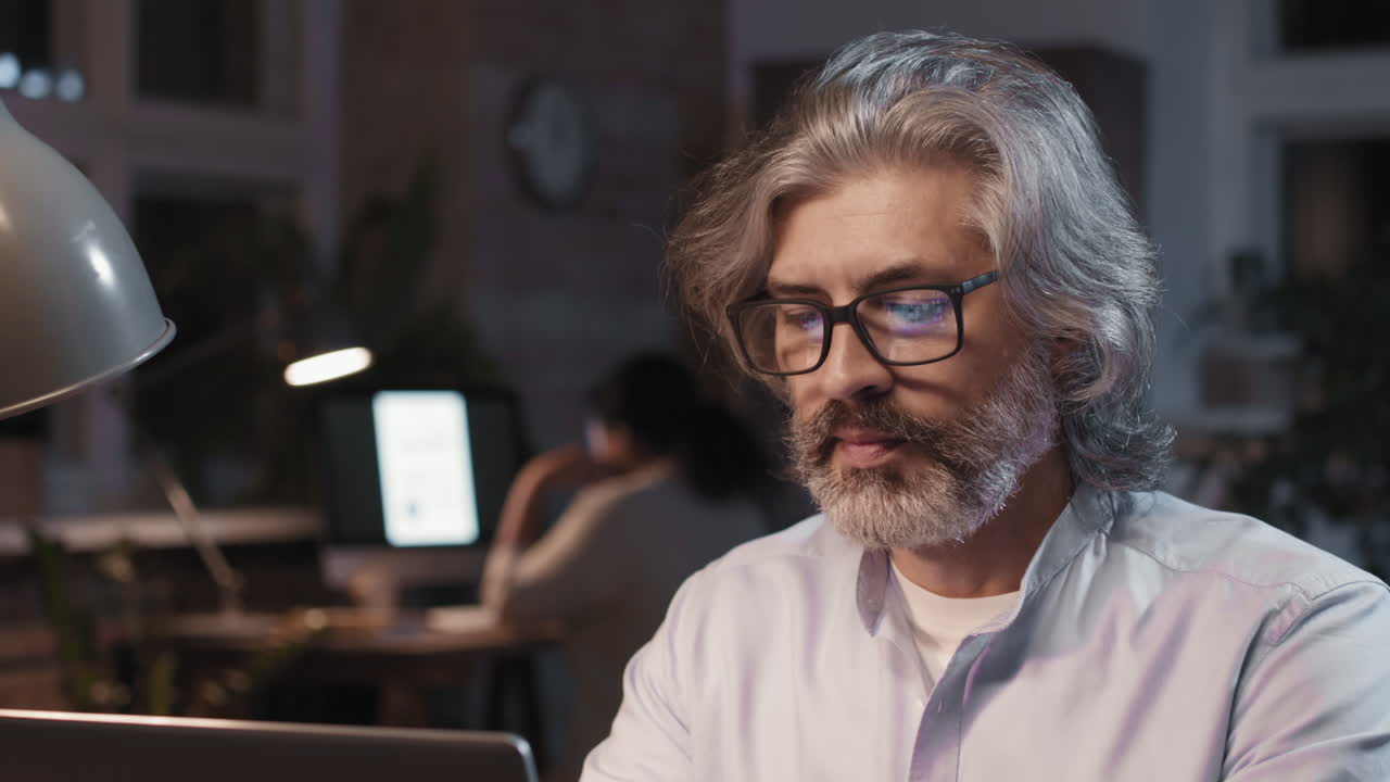 Mature Businessman Working Late on Laptop in Office at Night