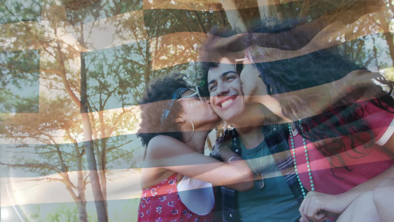 Two women playfully kissing man's cheeks over waving Greek flag animation