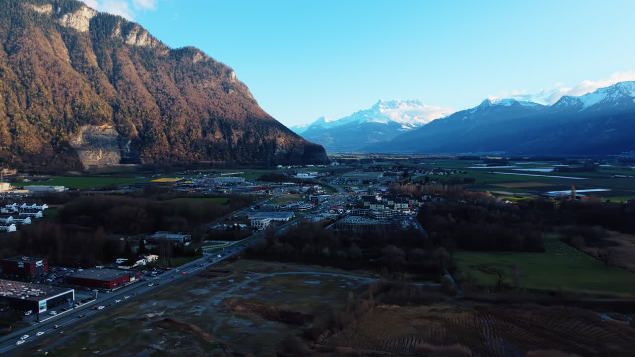 Ripresa aerea: Dents du Midi e zona industriale di Villeneuve al tramonto nel Canton Vaud, Svizzera, ripresa orbitale con drone.