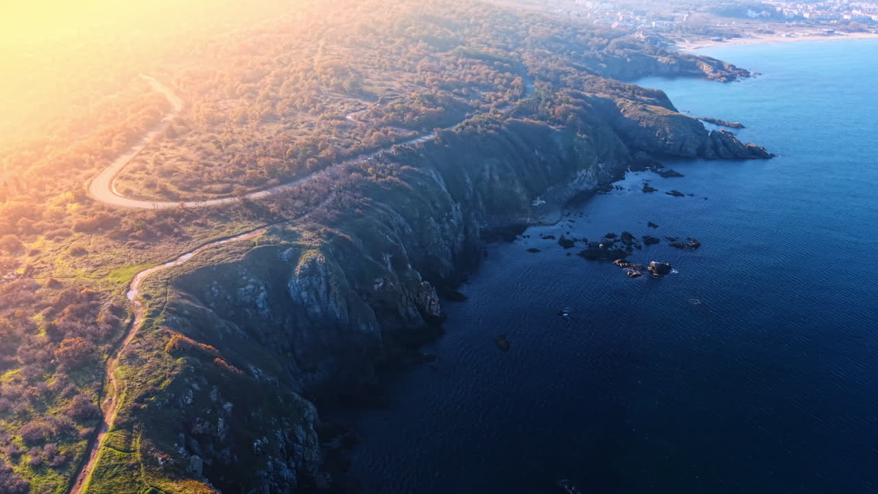 Paisaje deslumbrante por el sol de la costa rocosa cubierta de vegetación. Vídeo de dron sobre el paisaje acuático en la costa con acantilados.