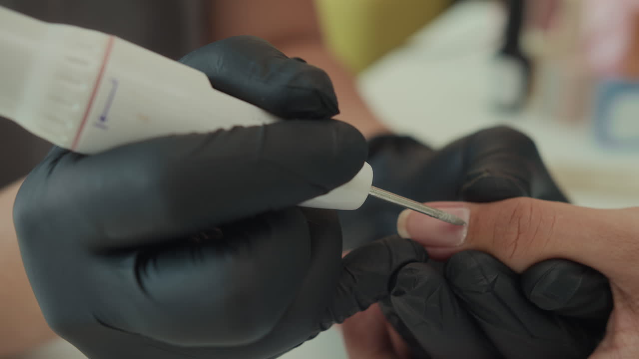 Gloved Hands of Specialist Doing Cuticle Removal on Nails of Client