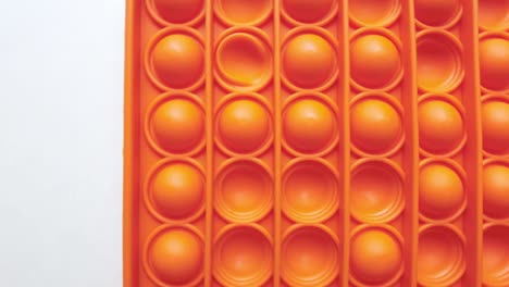 new baby toy. pop it finger play. funny color. colorful game spin on white table. orange square