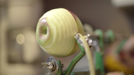 close up of a manual apple peeler skinning the peel from an apple