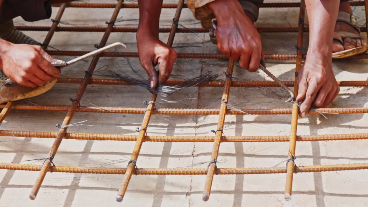 construction workers tying steel reinforcement bars using binding wire at a building site. day time, slight pan shot, 4k