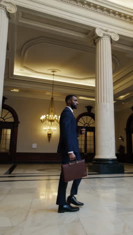 businessman walking through a grand building lobby towards large ornate doors