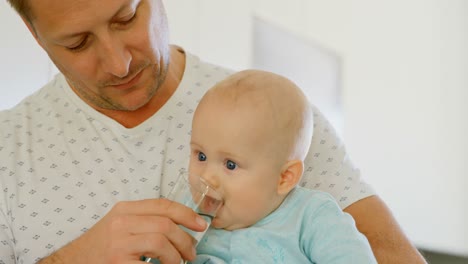padre alimentando con agua a su bebé 4k