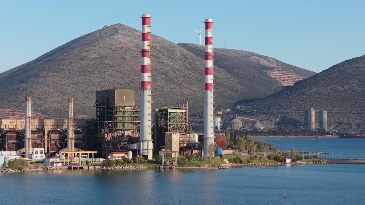 Un drone orbita e rivela la centrale elettrica di Aliveri lungo la costa dell'Eubea, mostrando la sua presenza industriale vicino al mare