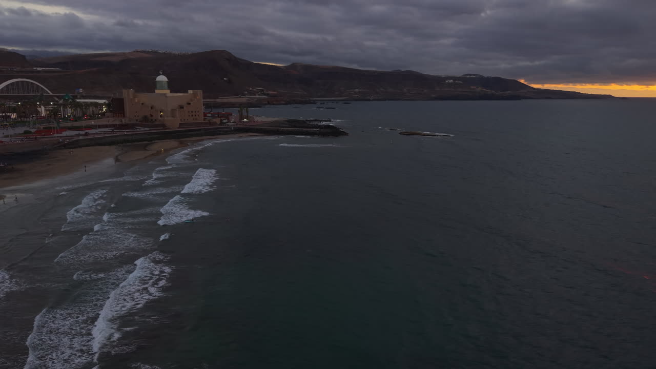 Waves rolling on Las Canteras beach at sunset with Alfredo Kraus auditorium, Las Palmas, Gran Canaria