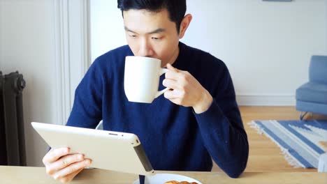 man using digital tablet while having cup of coffee 4k