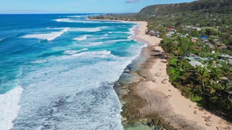 Imágenes-De-Drones-Sobrevolando-La-Costa-Norte-De-Oahu,-Toma-Aérea-De-La-Costa-Arenosa,-Olas-Blancas-En-El-Emblemático-Lugar-De-Surf-Junto-A-La-Ciudad-De-Hale&#39;iwa