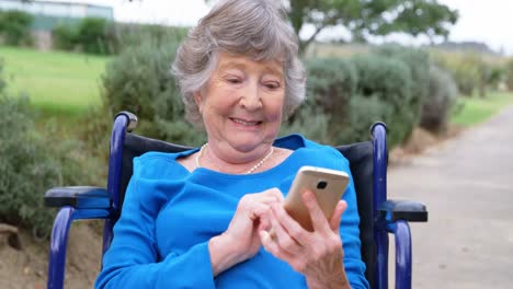 mujer mayor usando teléfono móvil en silla de ruedas 4k
