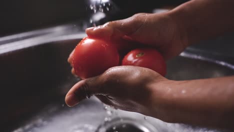 crop man washing ripe tomatoes in sink