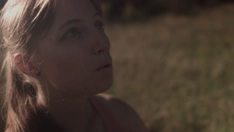 a girl is shown in close-up while taking a deep breath, gazing at the sky, and then closing her eyes for meditation