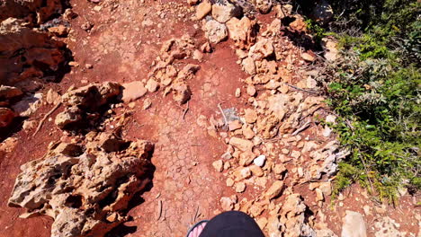 person walking on a rocky red earth path
