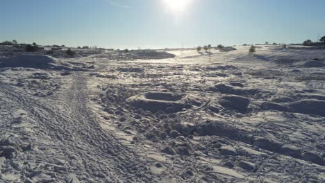 snow covered rural winter countryside track footprint shadows terrain aerial descend to low right view