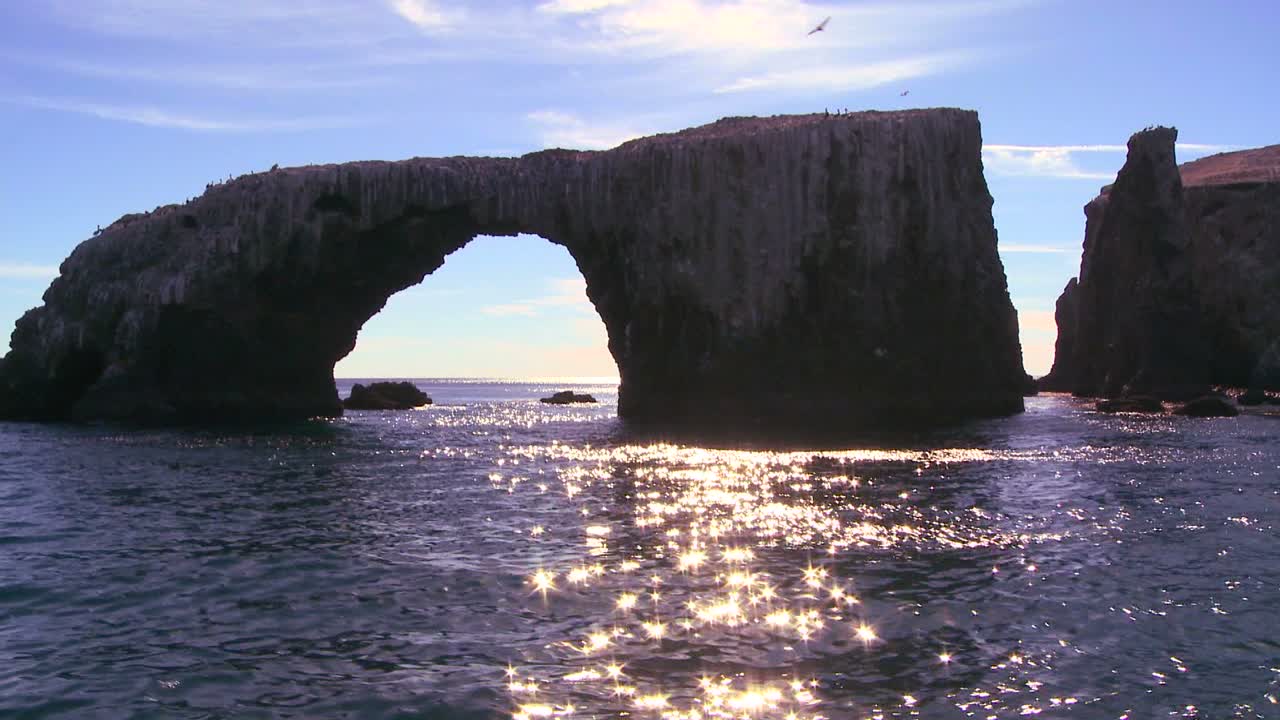 채널 제도 국립공원의 아나카파 섬 상징적인 자연 다리 옆 바다에서 햇빛이 반짝입니다.