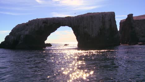 la luz del sol brilla en el mar junto al icónico puente natural de las islas anacapa en el parque nacional de las islas del canal