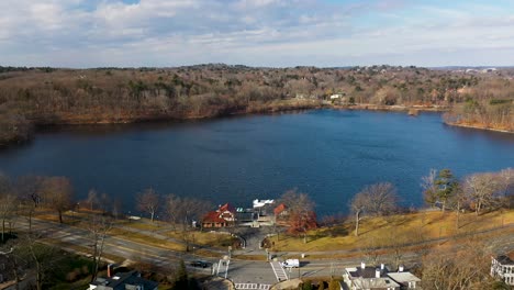 drone volando hacia un gran lago en un vecindario de boston en la primavera