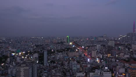 Ciudad-De-Ho-Chi-Minh,-Noche-De-Vietnam-Con-Canal,-Edificio-Emblemático-Y-Vista-Sobre-Los-Tejados-A-La-Expansión-Urbana-Y-La-Carretera-Principal-Bajo-Las-Luces