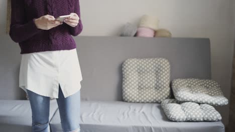 Young-woman-using-mobile-phone-in-home-room.-Girl-typing-message-on-smartphone