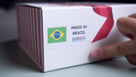 Hände-Bringen-Das-In-Brasilien-Hergestellte-Flaggenetikett-Auf-Einem-Versandkarton-Mit-Produkten-An