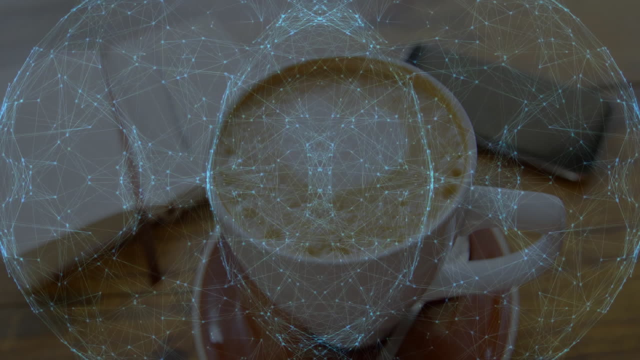 White ceramic coffee cup being placed on brown saucer in workspace, with notebook and smartphone