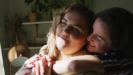 pareja de lesbianas caucásicas abrazándose y mirando hacia otro lado
