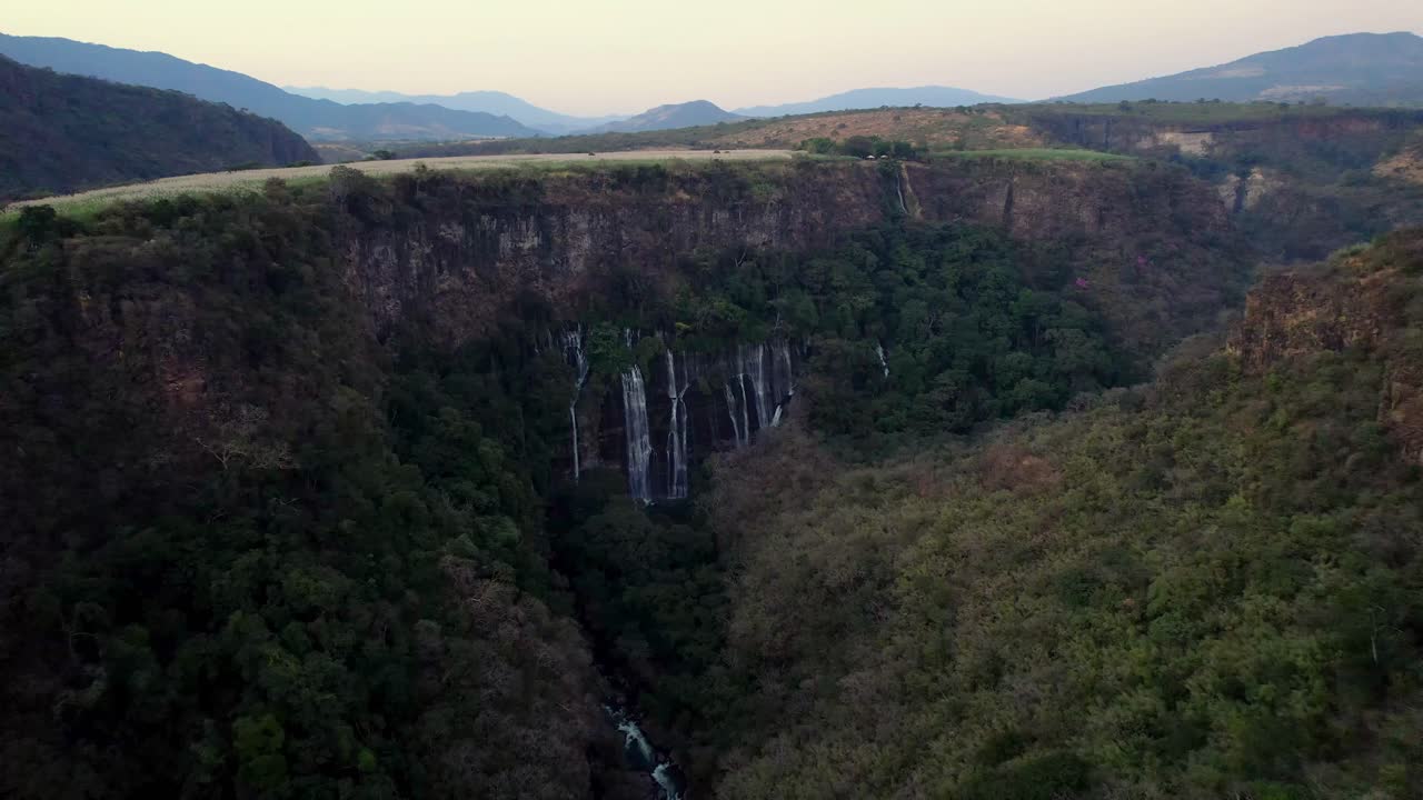antena lenta siguiendo el río que conduce a una cascada de montaña cubierta de árboles verdes y exuberantes en michoacán, méxico