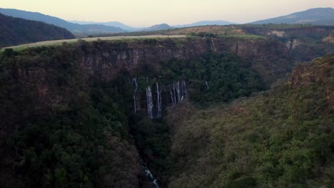 Langsame-Luftaufnahme-Des-Flusses,-Der-Zu-Einem-Mit-Grünen,-üppigen-Bäumen-Bedeckten-Bergwasserfall-In-Michoacán,-Mexiko,-Führt